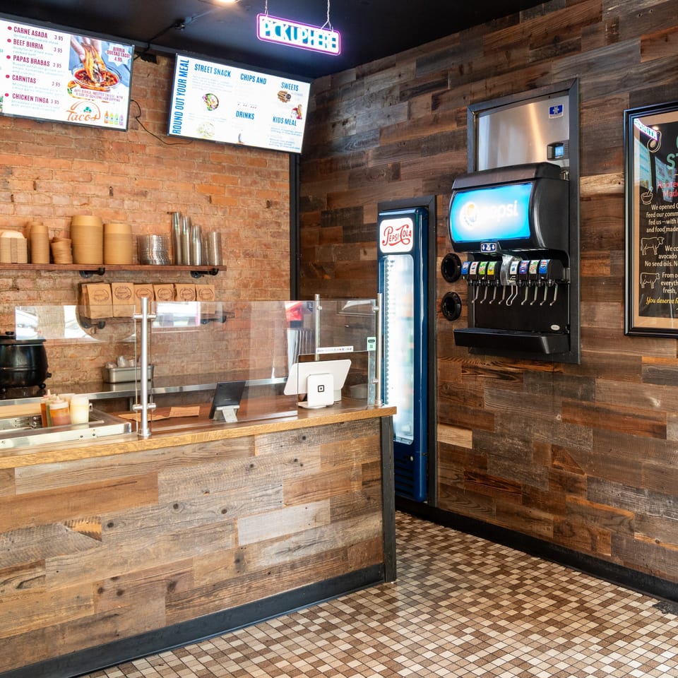 Chilango's Burrito Bar interior with a wooden counter, menu screens, and a Pepsi soda fountain.